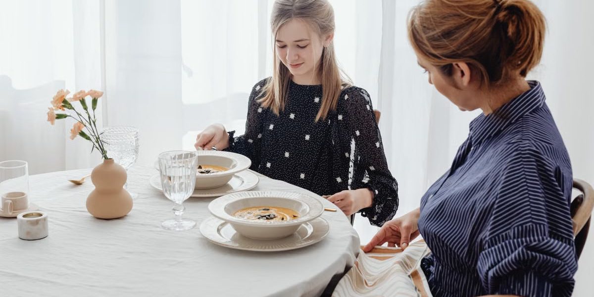A serene scene of a mother and daughter dining together in a bright, cozy setting.